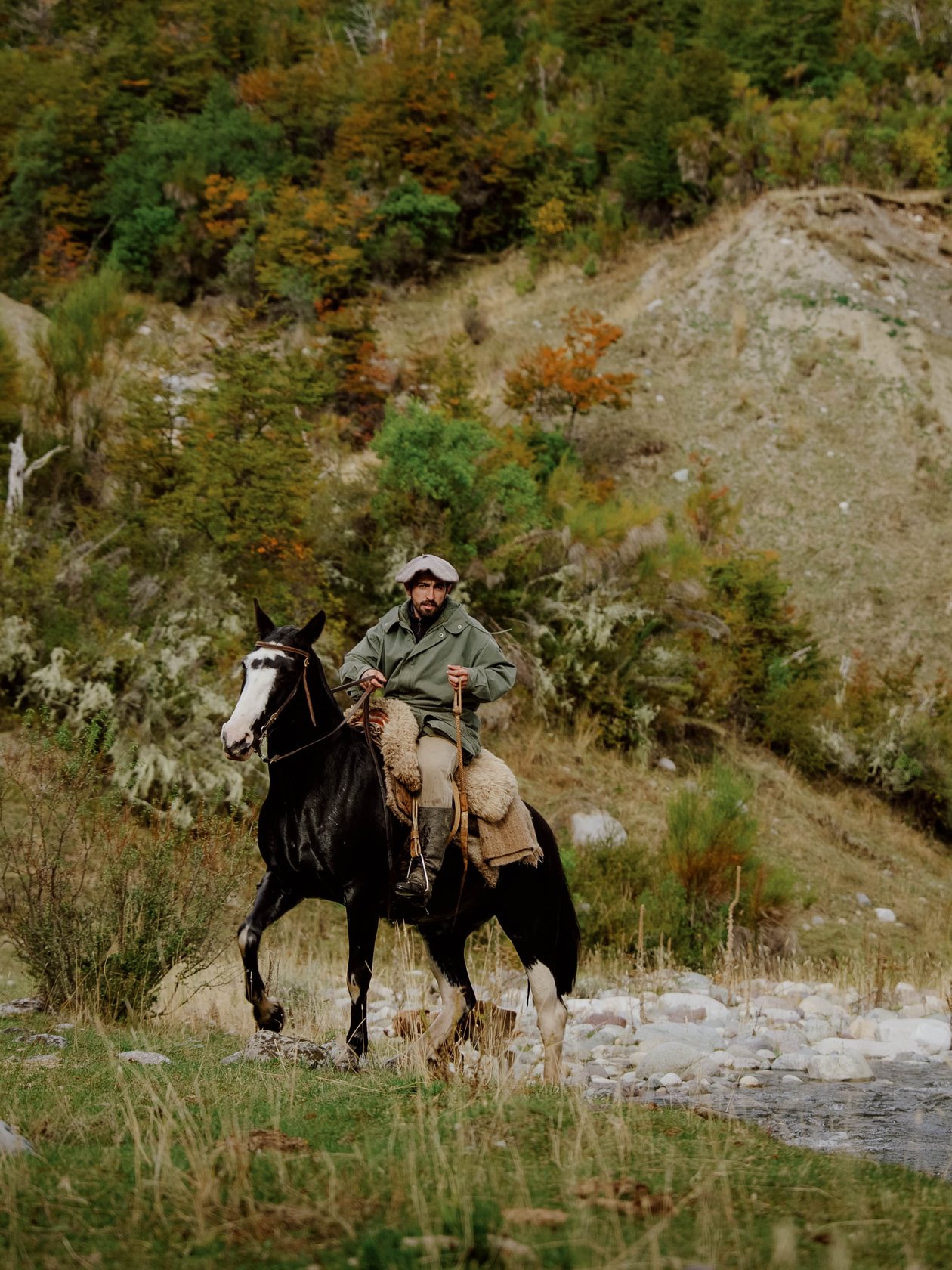 Gaucho on horseback by a river in autumn, Patagonia
