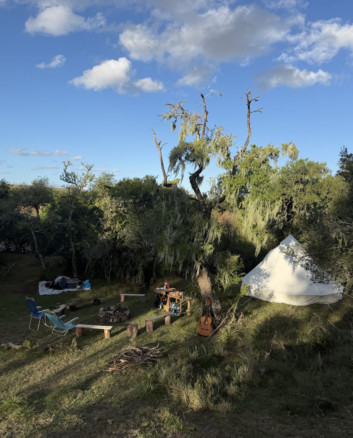 Camp beneath the trees — bell tents, fire and a guitar, Uruguay